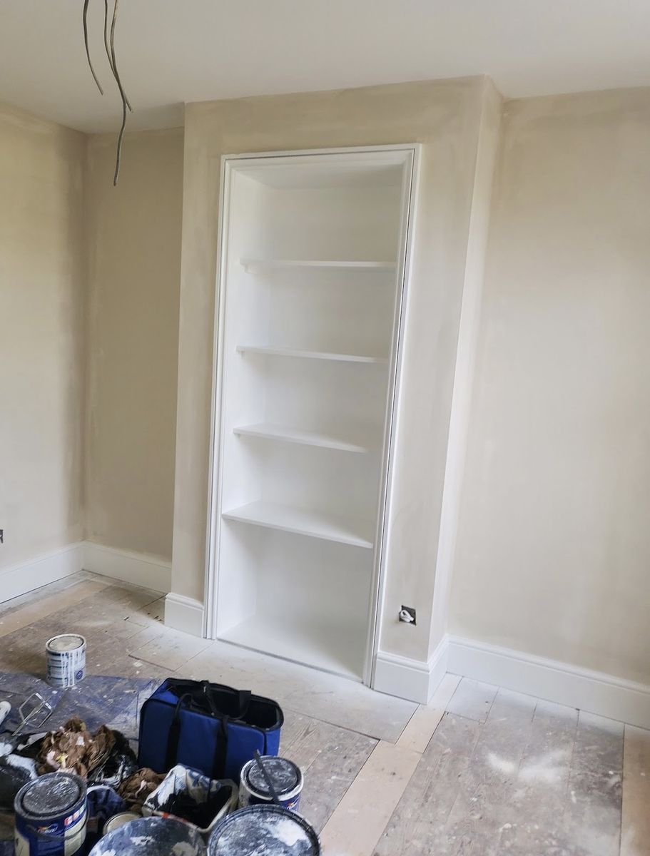 The same room with walls in a warm neutral and the alcove shelving finished crisp white