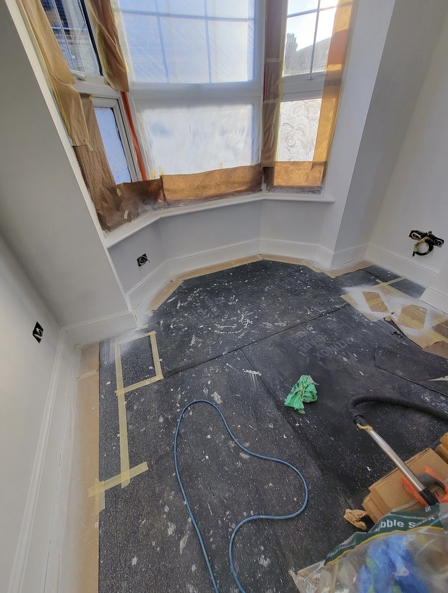 A bay window masked up with paper and tape, floor protected, ready to spray