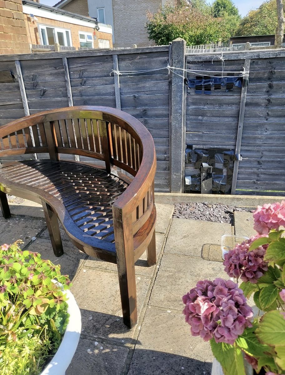 A weathered garden bench with patchy, worn slats part-way through stripping