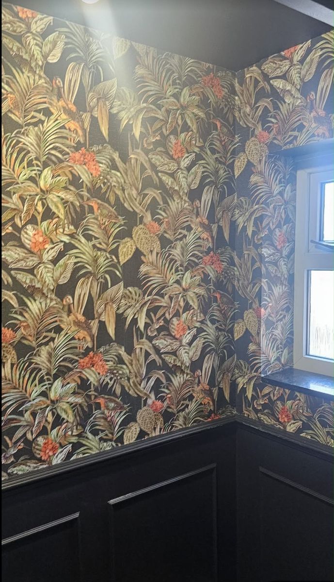 The finished wall: dark floral wallpaper above black panelling