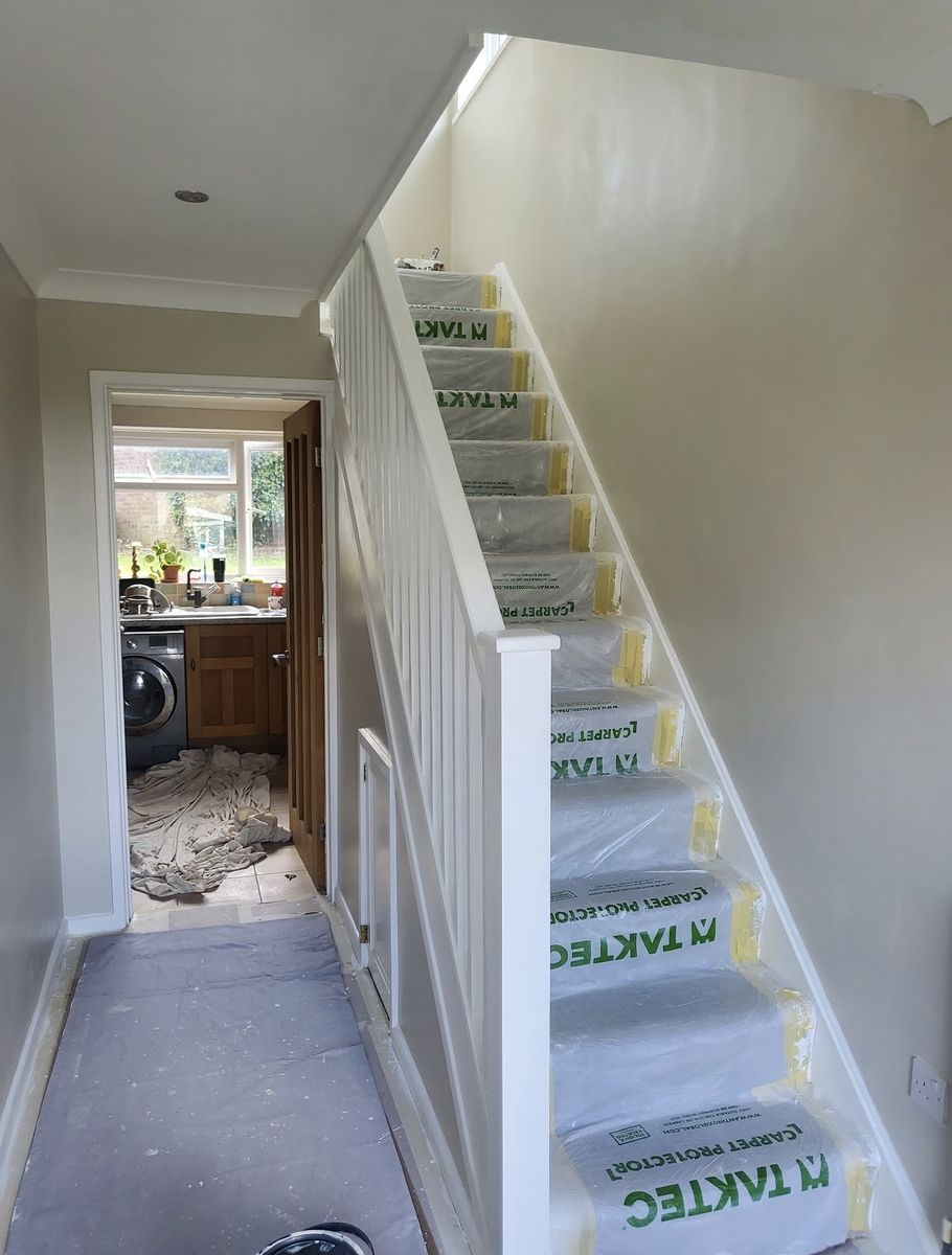 The same staircase mid-job, treads protected and woodwork painted